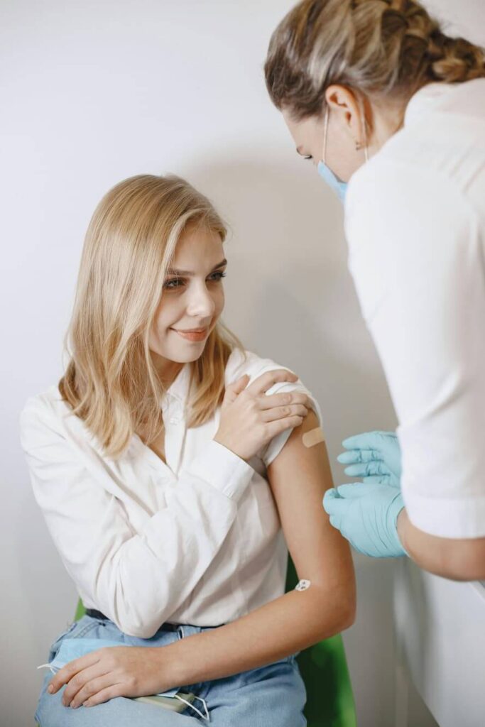Ärztin schaut auf den Arm einer Patientin mit Pflaster.