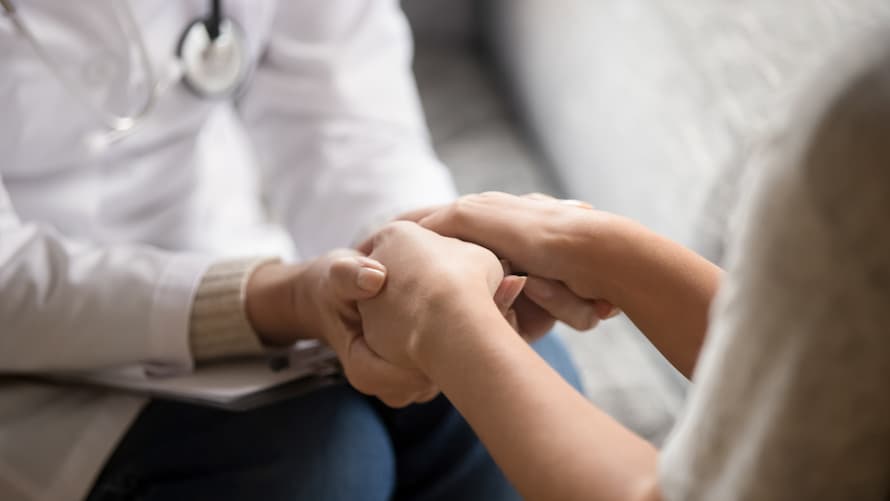 Ärztin hält die Hand einer Patientin.